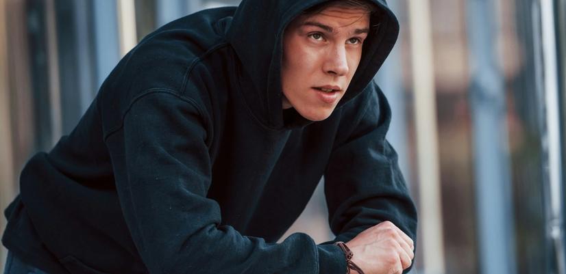 A young man leans on a railing, caught between uncertainty and possibility — a reminder of how crucial early support and guidance can be when finding your way forward.
