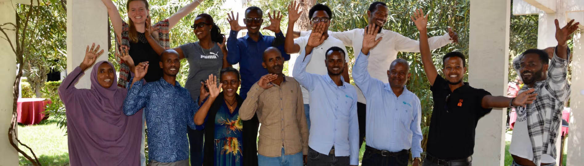 gruppebilde av 13 personer med hendene i været 