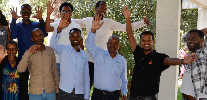 gruppebilde av 13 personer med hendene i været