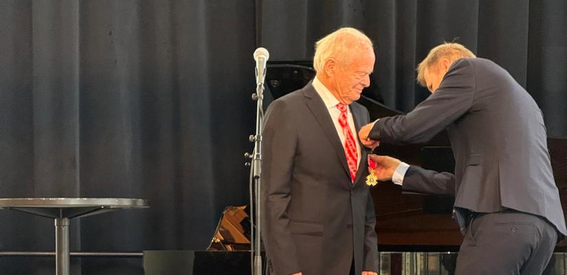 Mann hjelper mann med å feste medalje på brystet på en scene