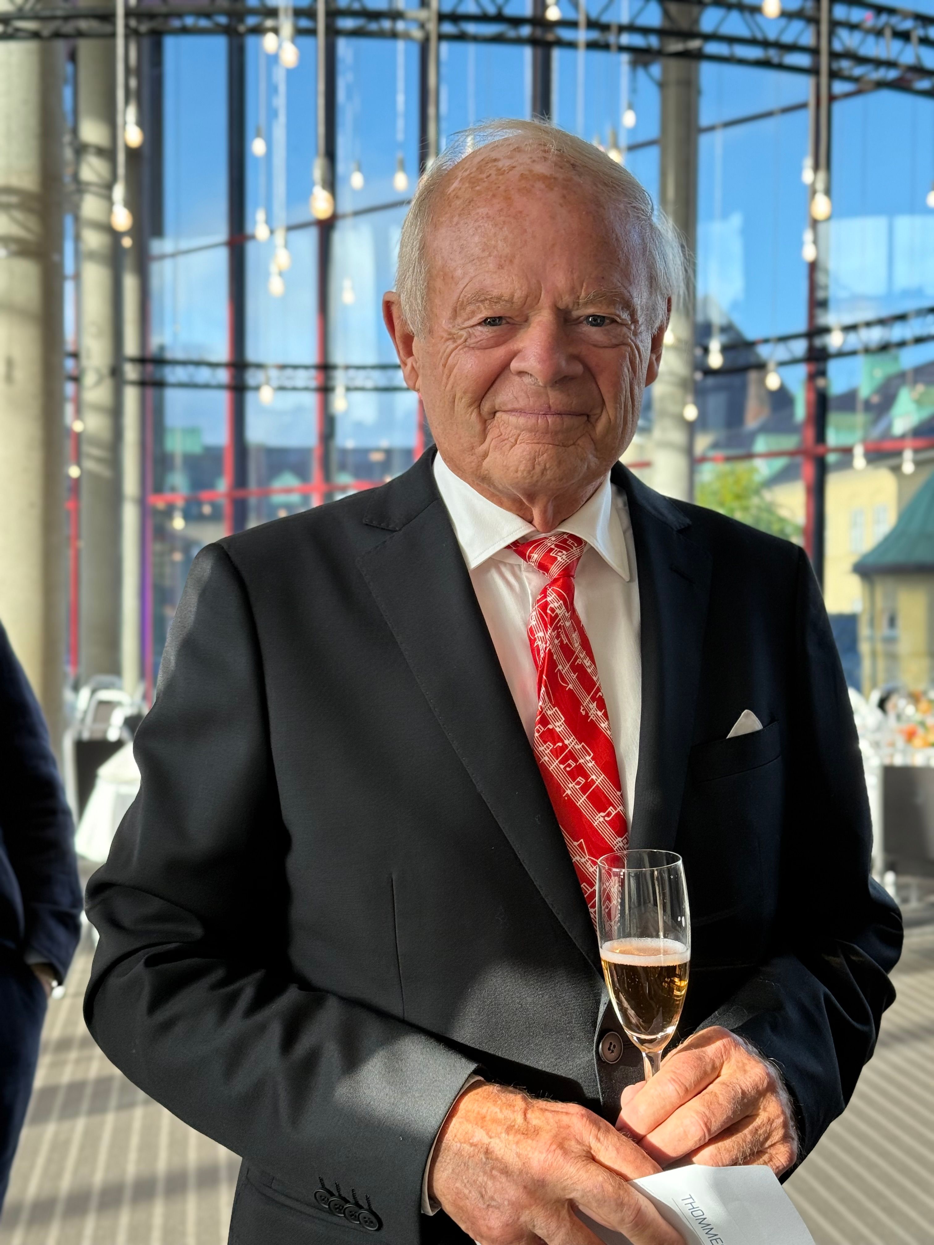 Mann I dress holder et stettglass i hånden 