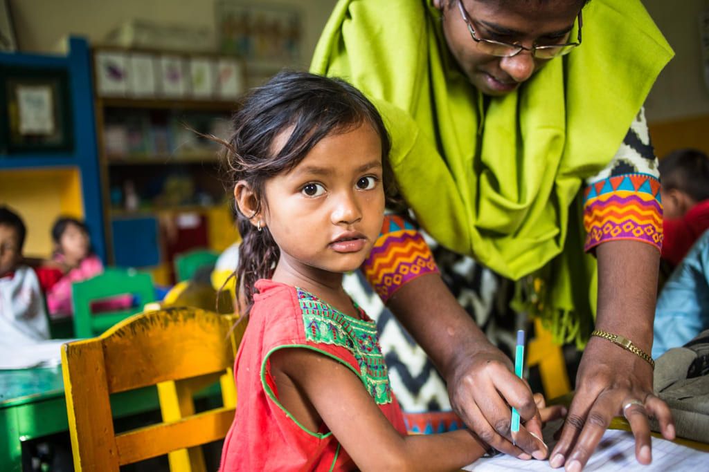 A young student is receiving support from her teacher.  