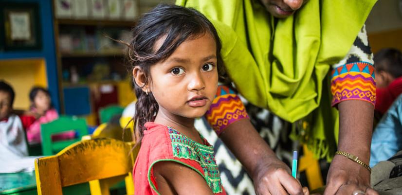A young student is receiving support from her teacher.