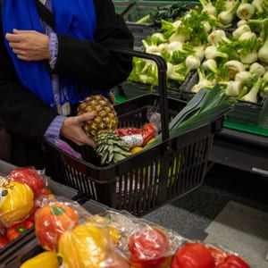 En kunde i butikken legger en ananas i handlekurven. 