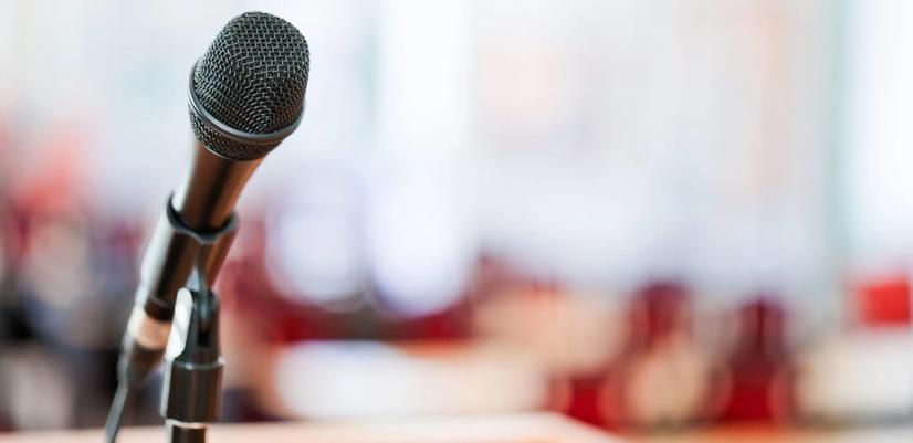 Close-up of a microphone on a stage. The background is blurred.