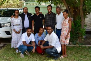 Ni personer står sammen i en gruppe ute. tre personer sitter på huk foran seks personer som står. 