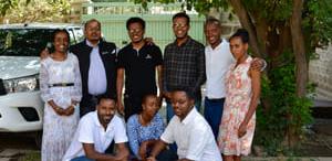 Ni personer står sammen i en gruppe ute. tre personer sitter på huk foran seks personer som står.