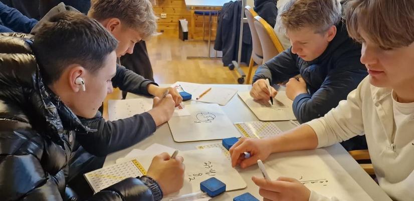 En guttegruppe sitter og jobber konsentrert med regnestykker under Campus UNG på Askøy.