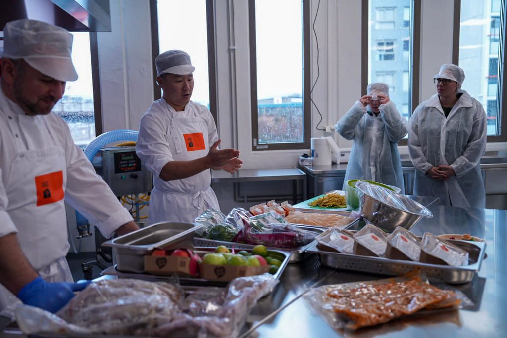 A team of chefs and young adults in work training reviewing ingredients for the day’s meals.
