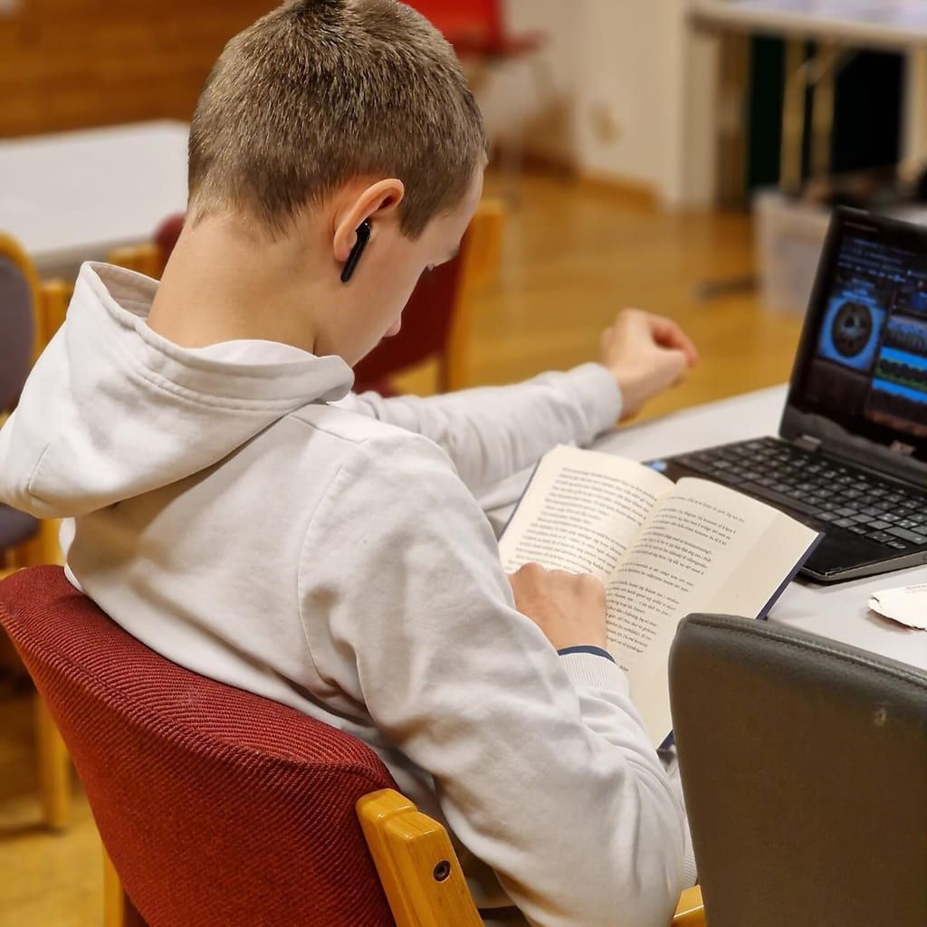En gutt sitter konsentrert og leser i en bok. 