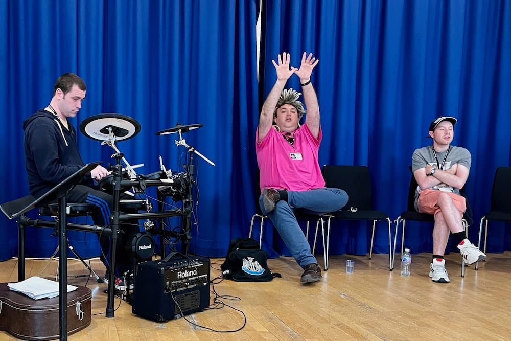 Tre deltakere i Music Spark øver på å fremføre sangen de har laget. De synger og spiller instrumenter. 