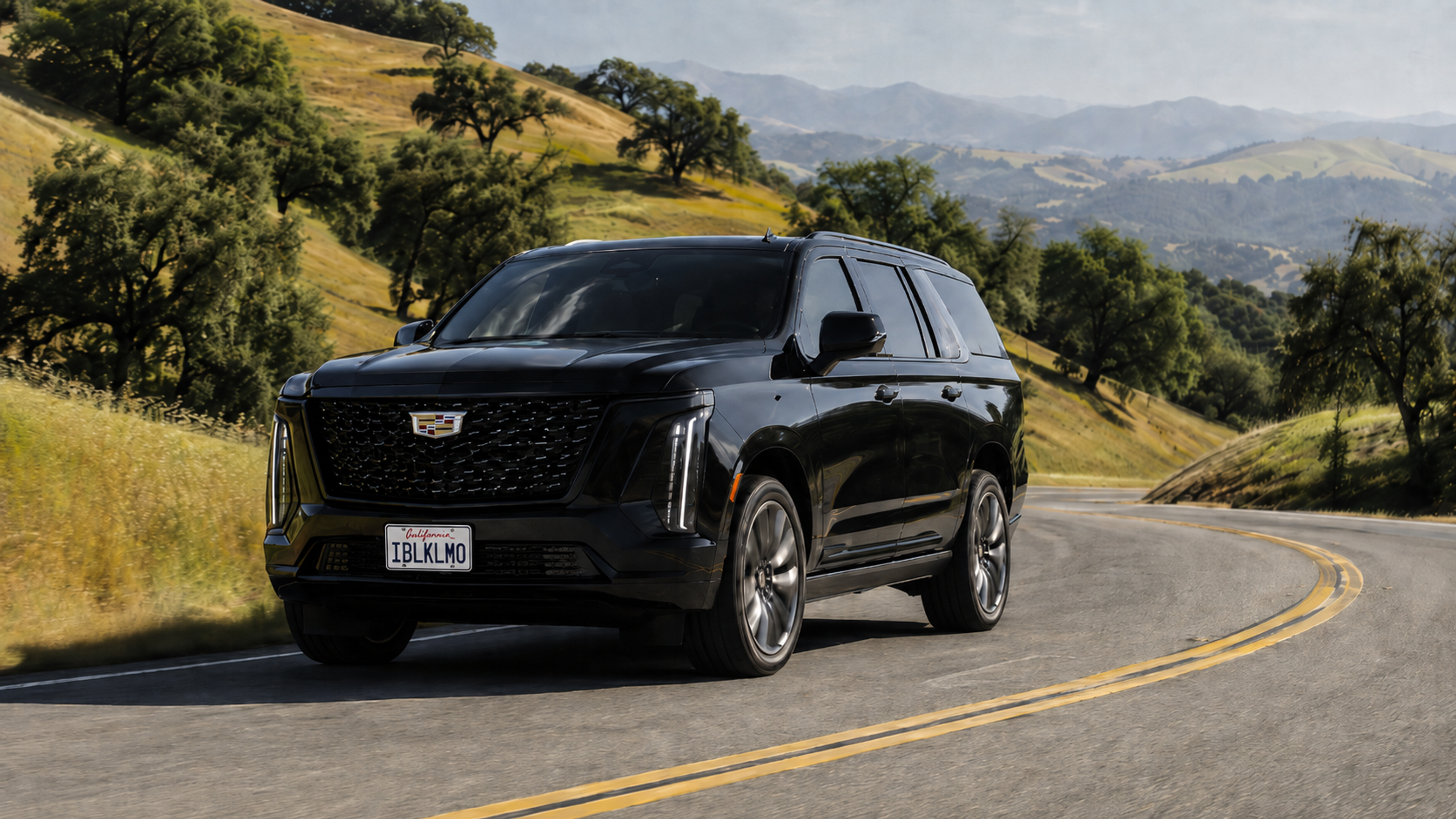 A black Cadillac sedan on a winding road through the oak-covered hills of Carmel Valley