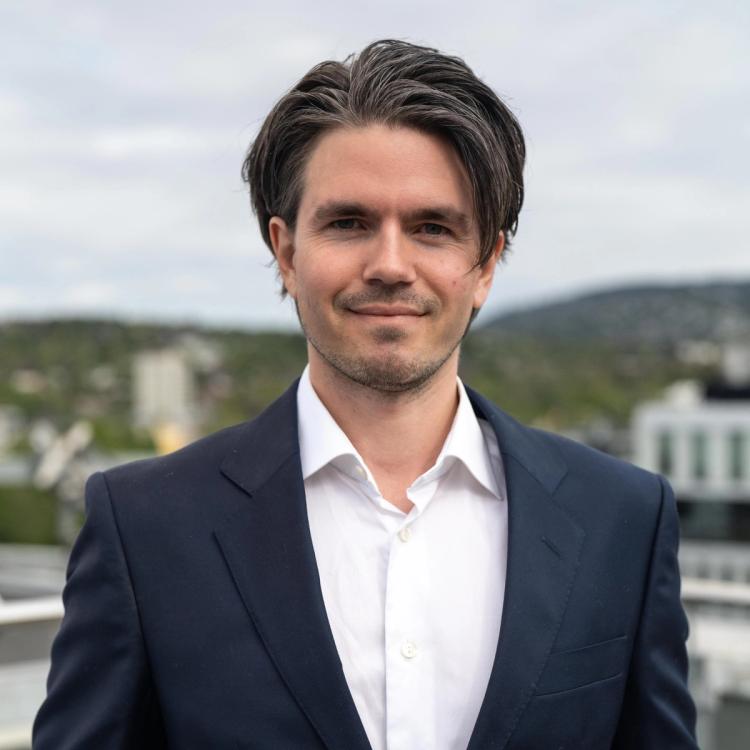 Portrett av en smilende og dresskledd Nicolai Q. Hjort. 