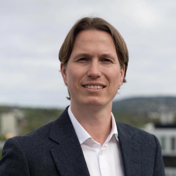 Nærbilde av en smilende og dresskledd Benjamin Haskel. 