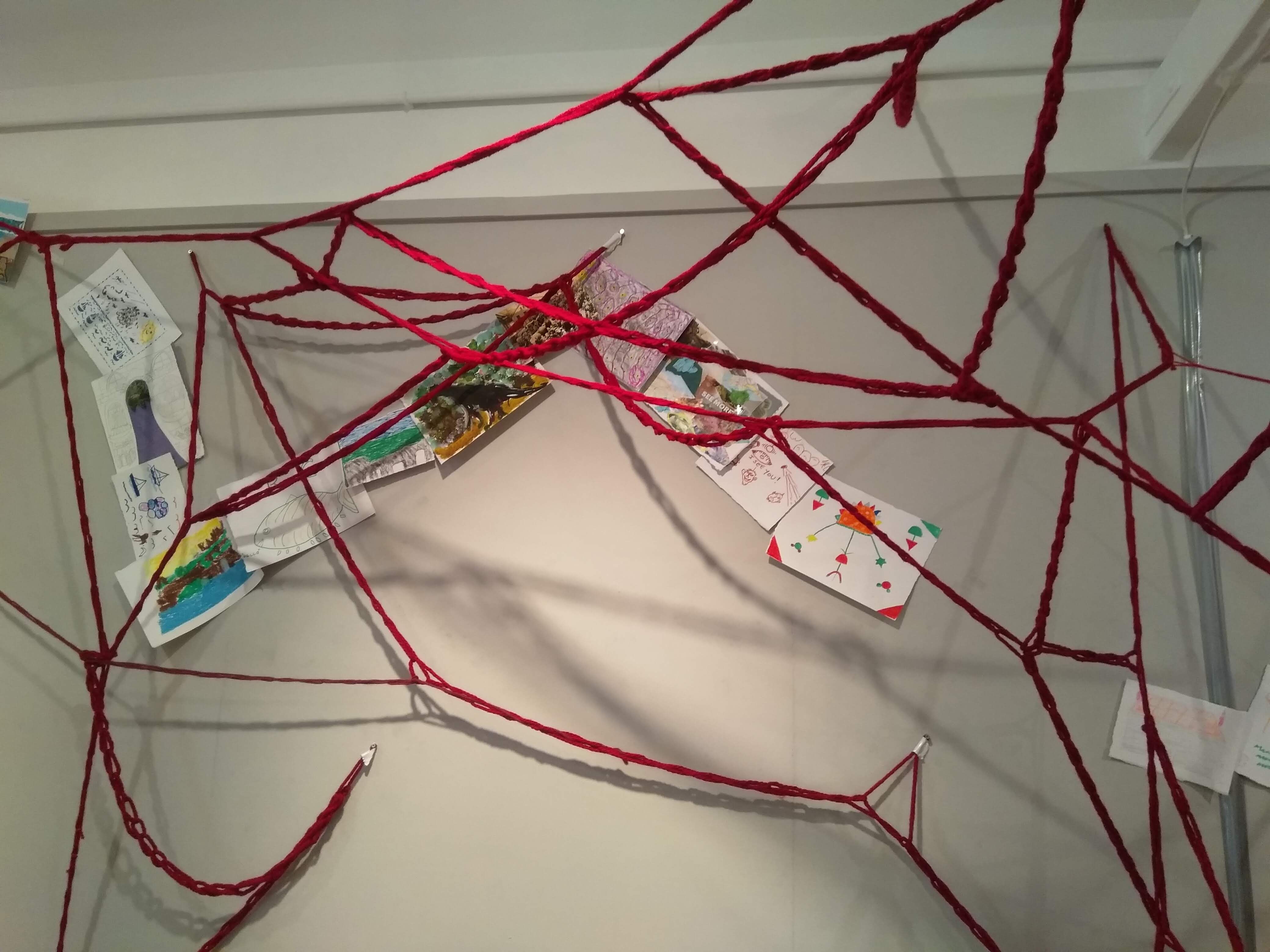 Close up of the installation A Collective Brain inclusing red criss crossed crochet chains and drawings