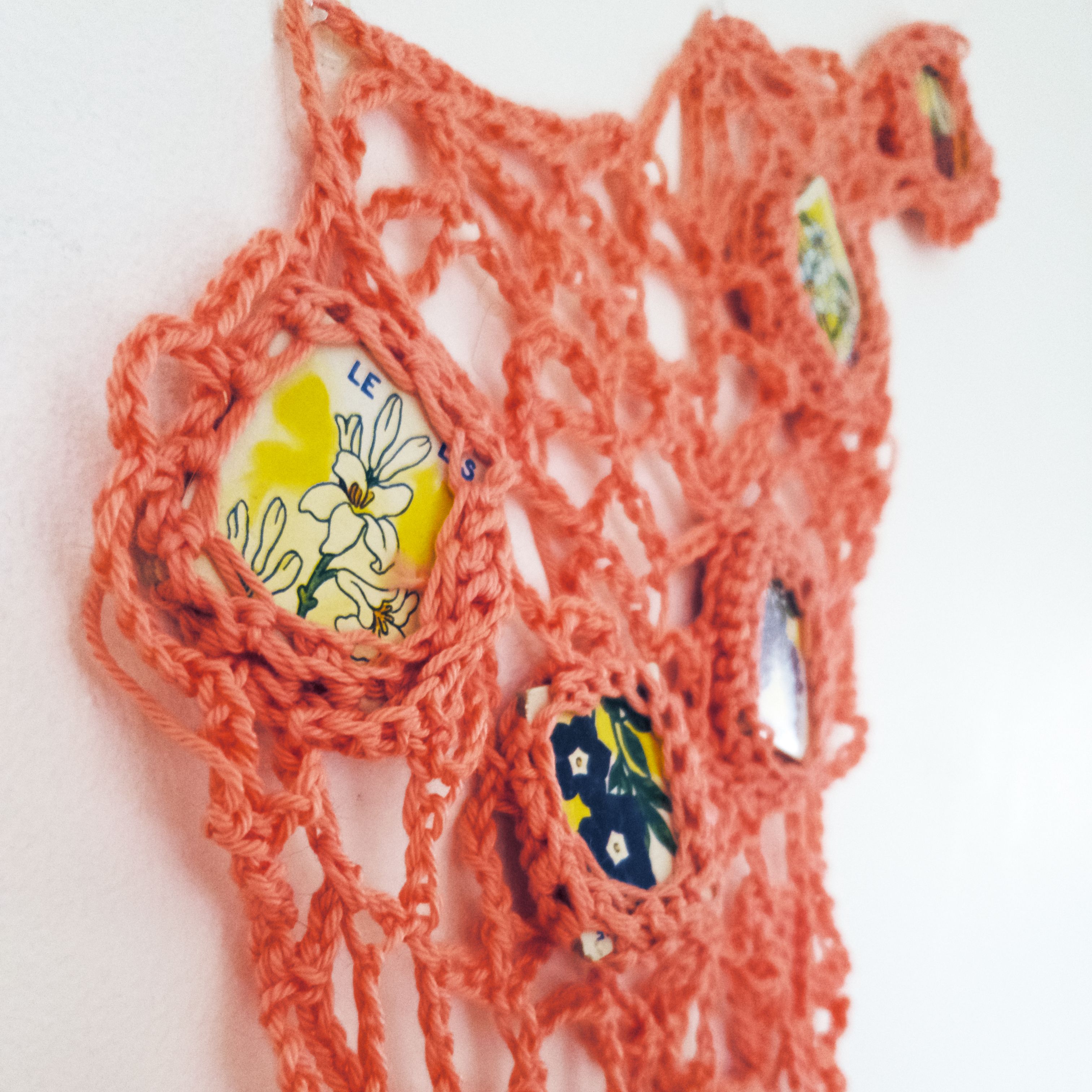 Close up of pink crochet sculpture with pieces of a French children's game