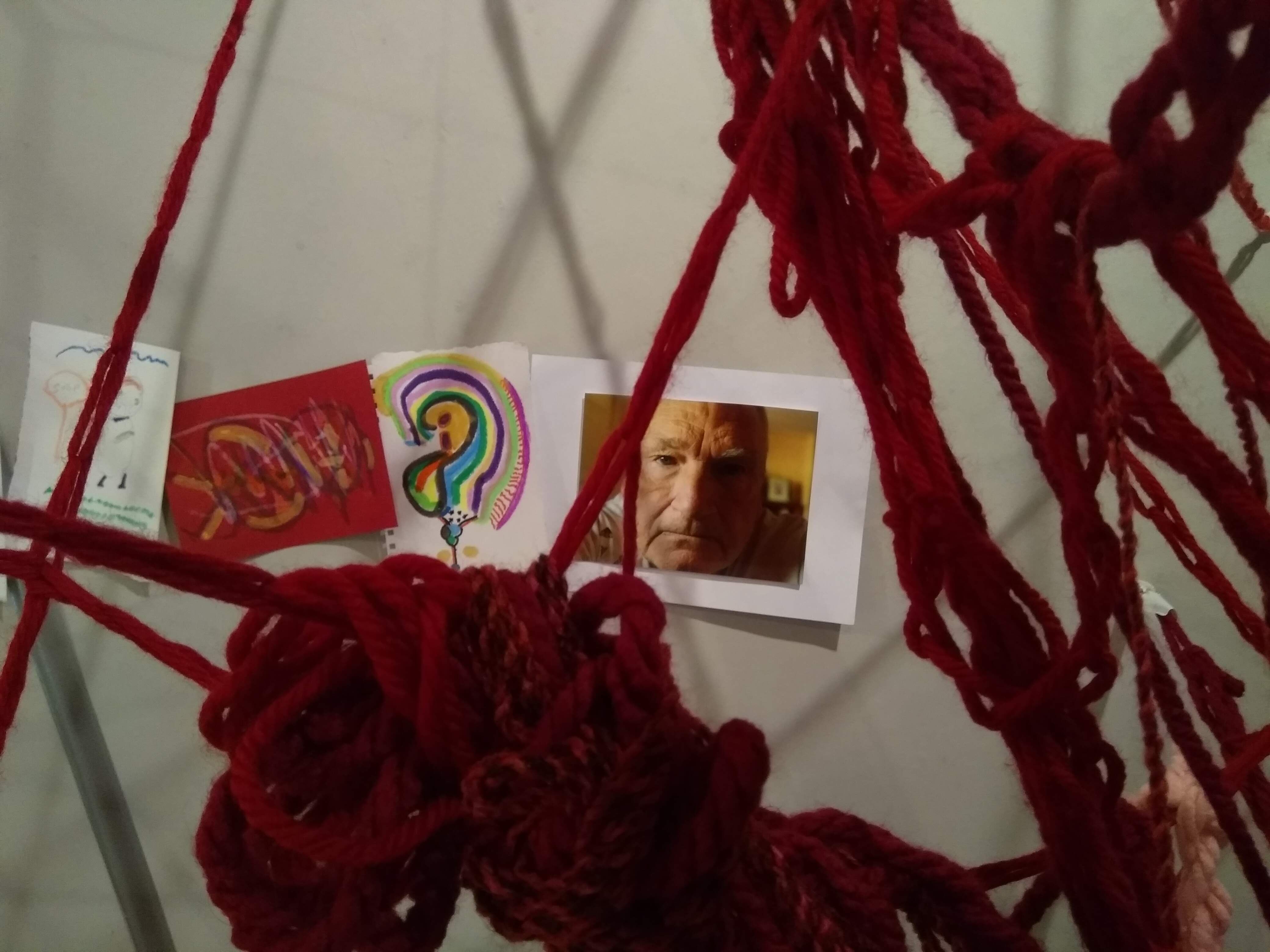 Close up of A Collective Brain installation showing red wool tangles, the photograph of an older man and drawings