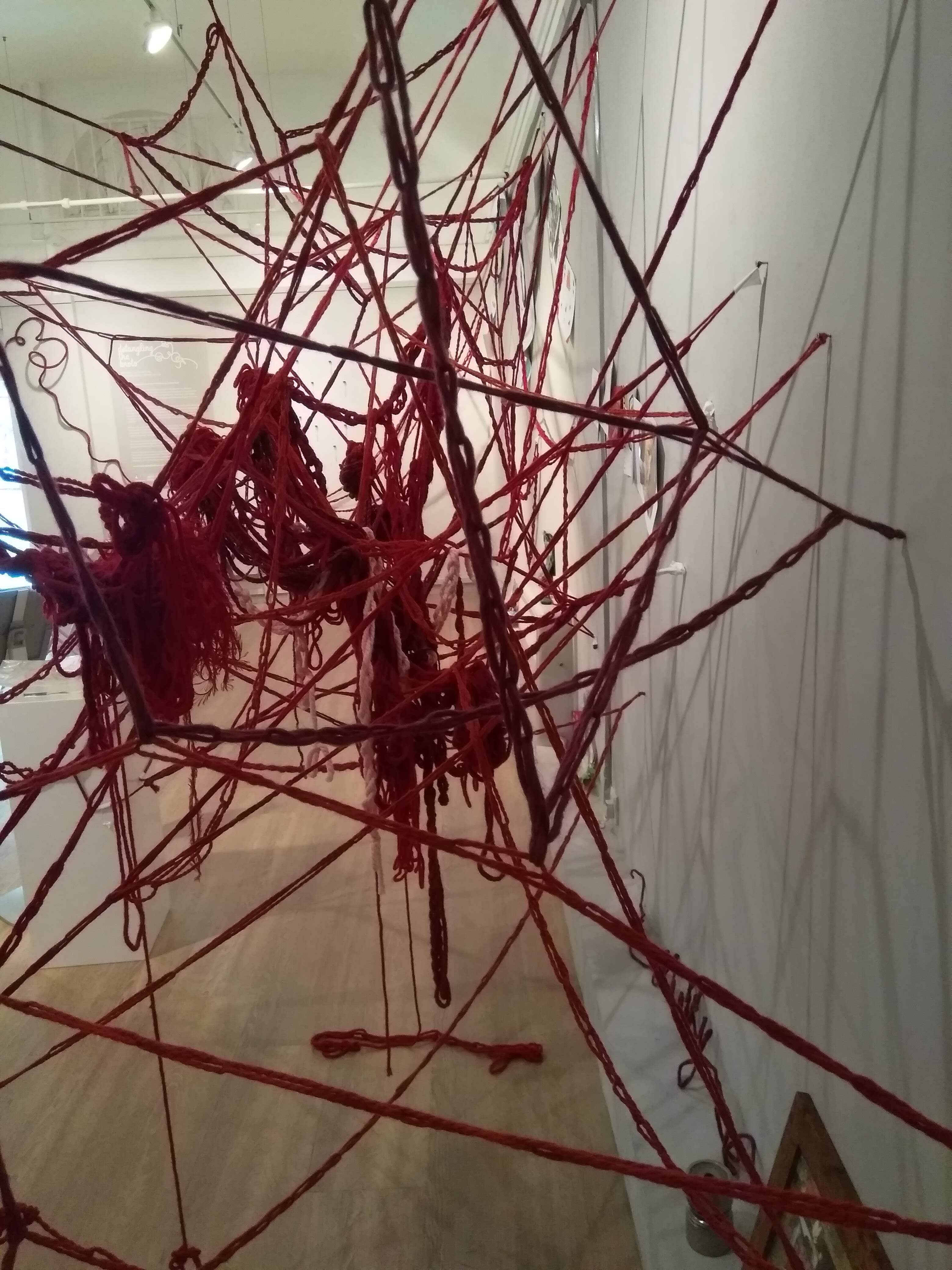Close up of installation A Collective Brain showing red crochet chains and wool tangles