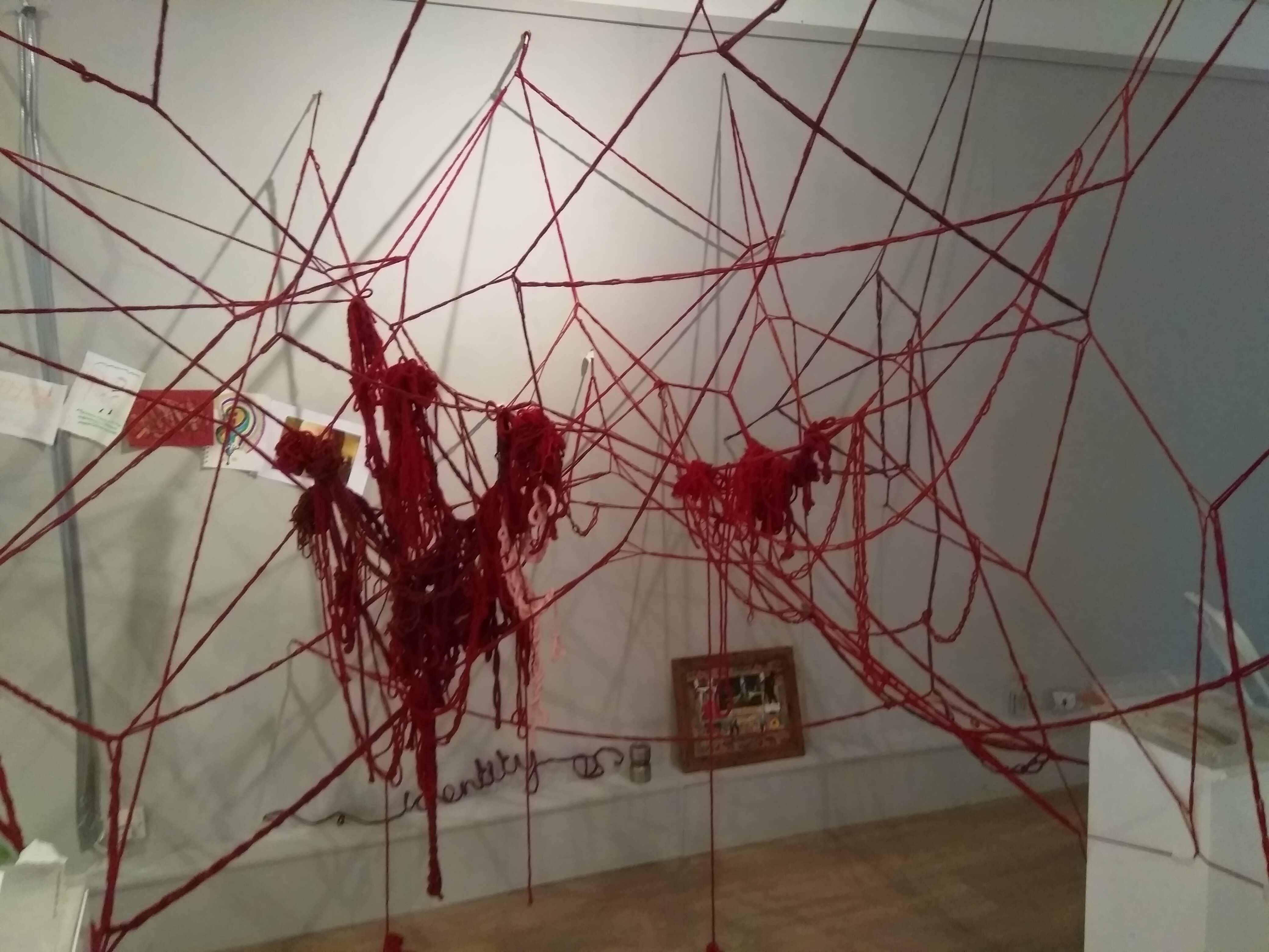A large 3d red wool installation with crochet chains, tangles and drawings