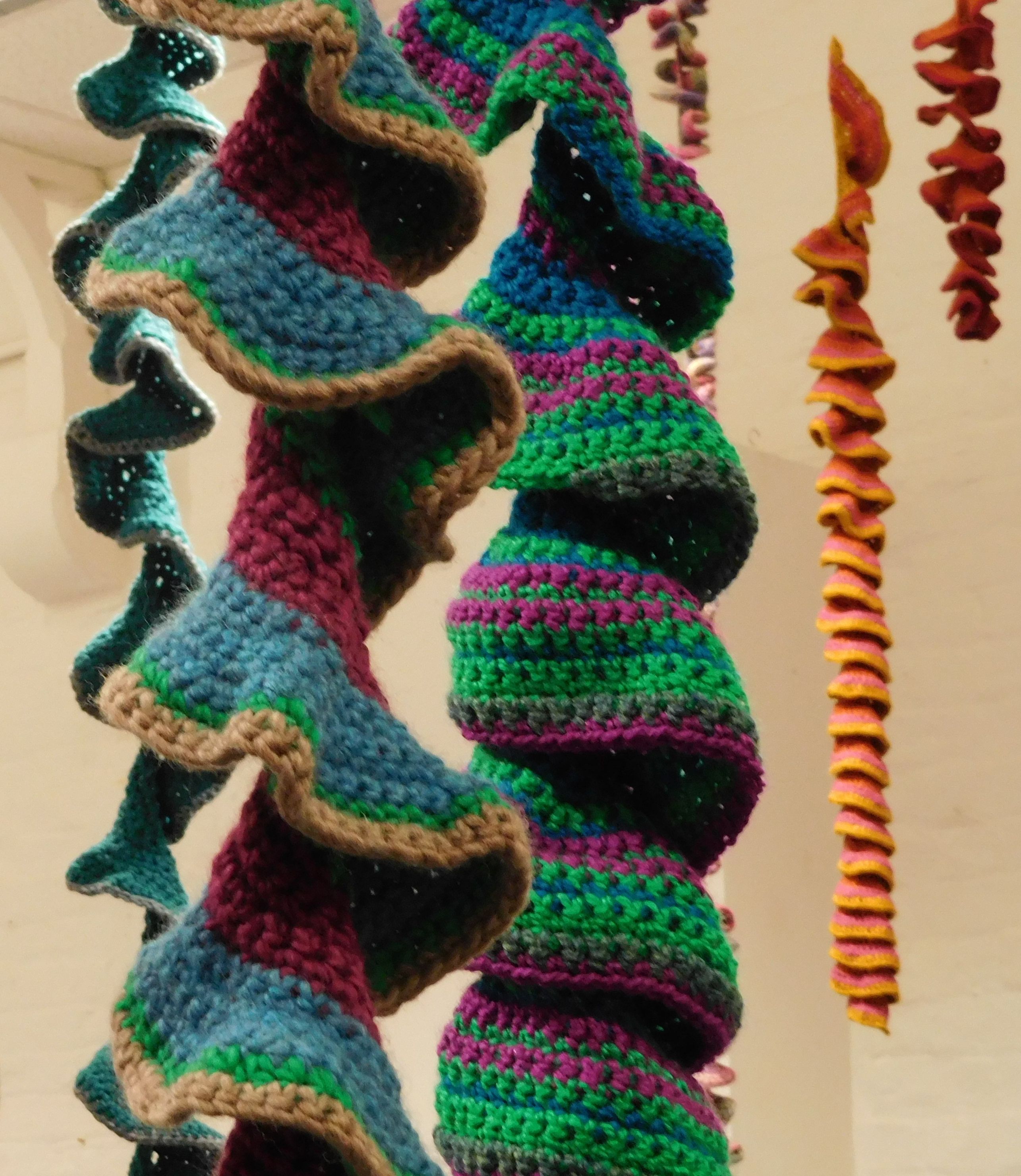 A series of hanging wool sculptures of various length in twisting shapes