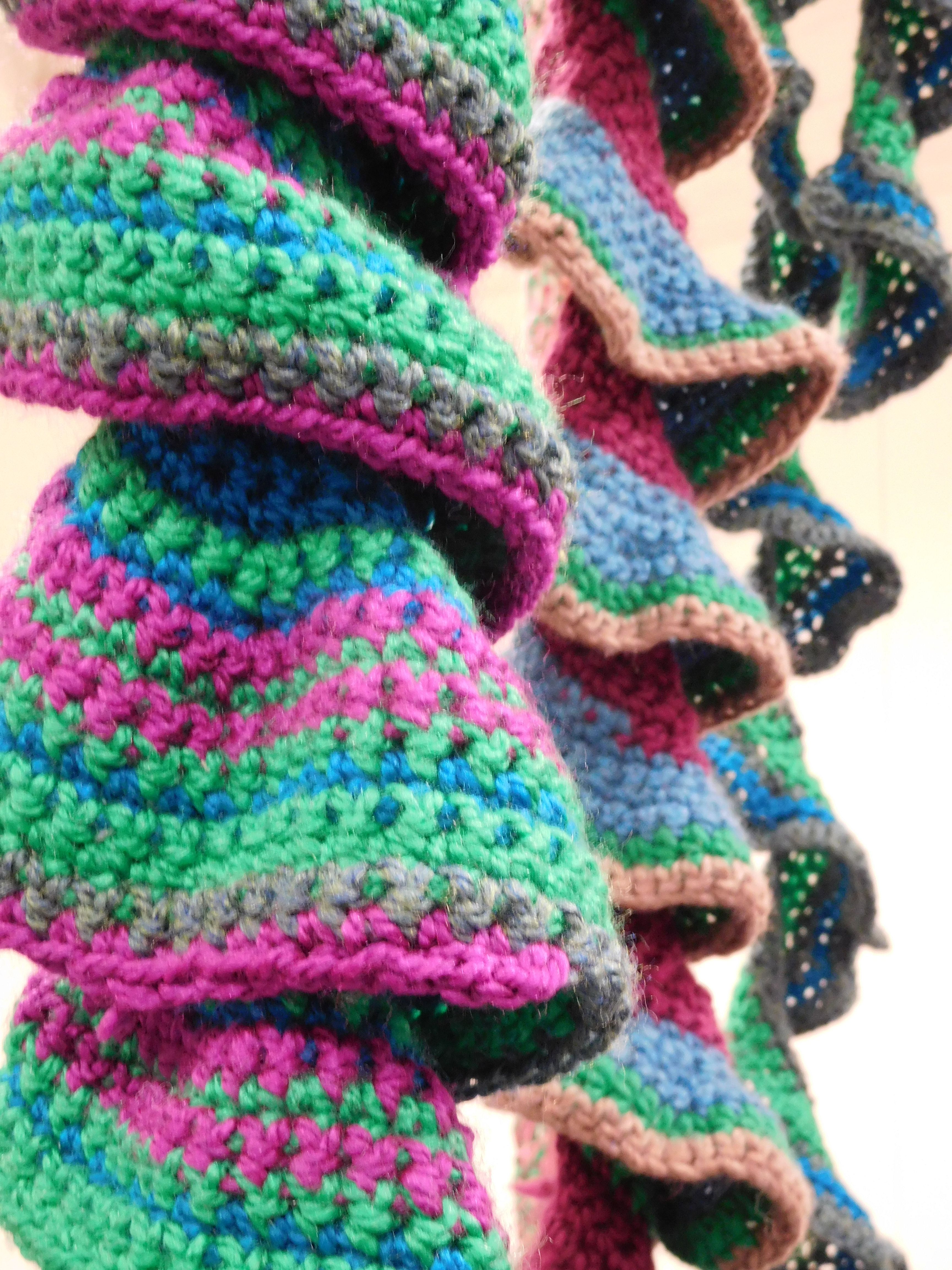 Close of hanging crochet sculptures in green and purple