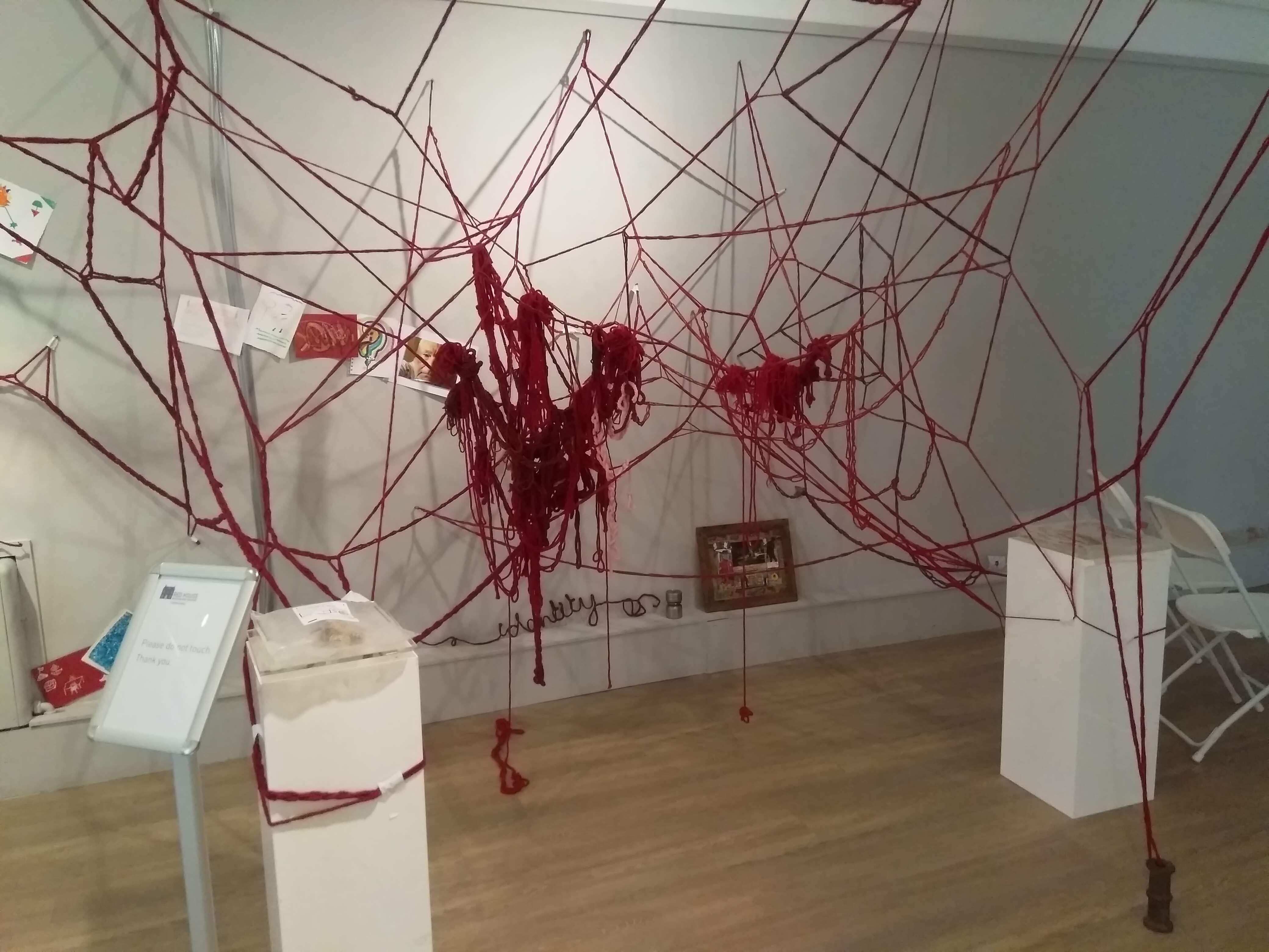 A large 3 d red wool installation with wool chains,  tangles and drawings