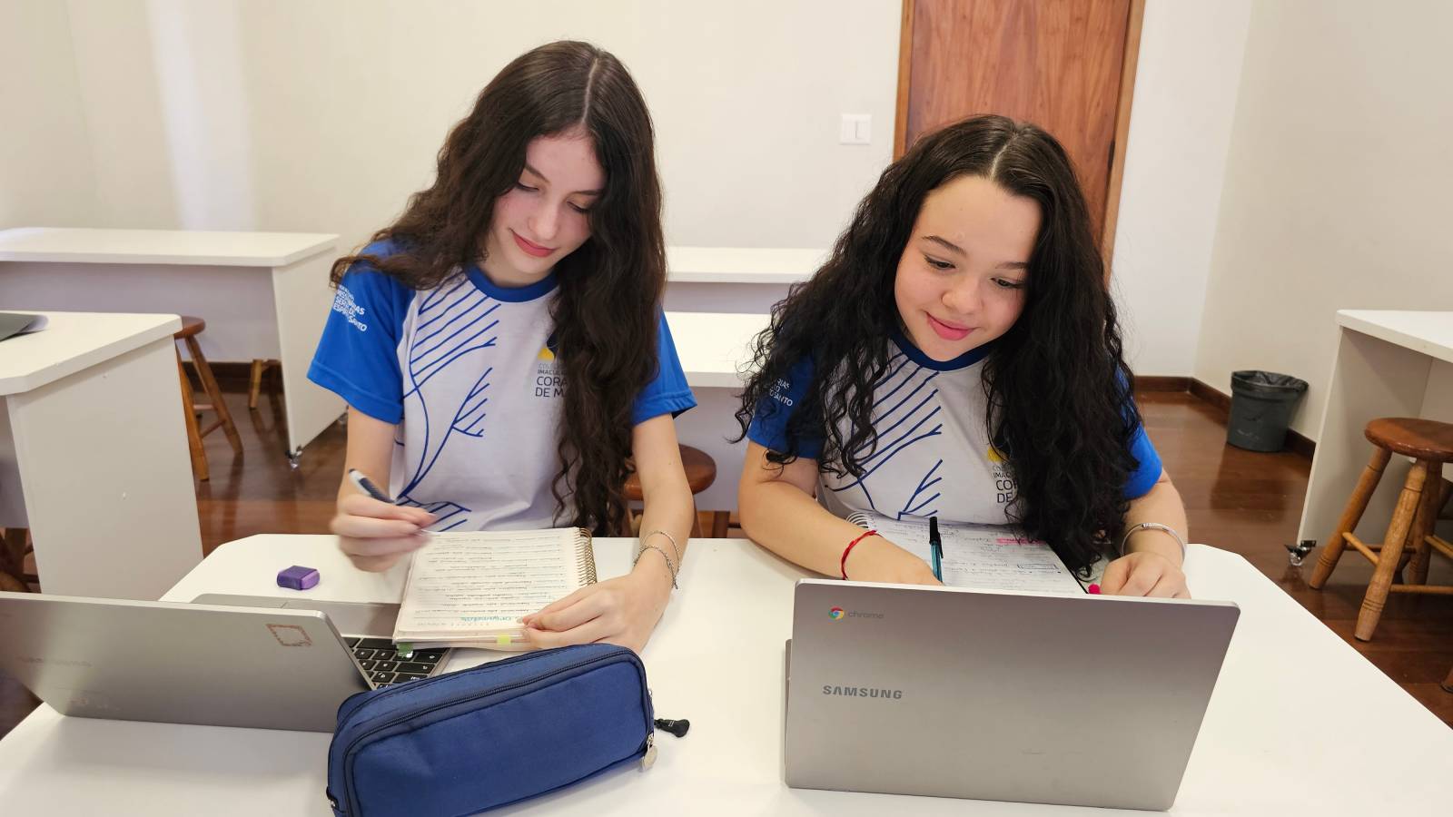 Duas estudantes do Ensino Médio estudam com cadernos e notebooks para o Projeto Aprova