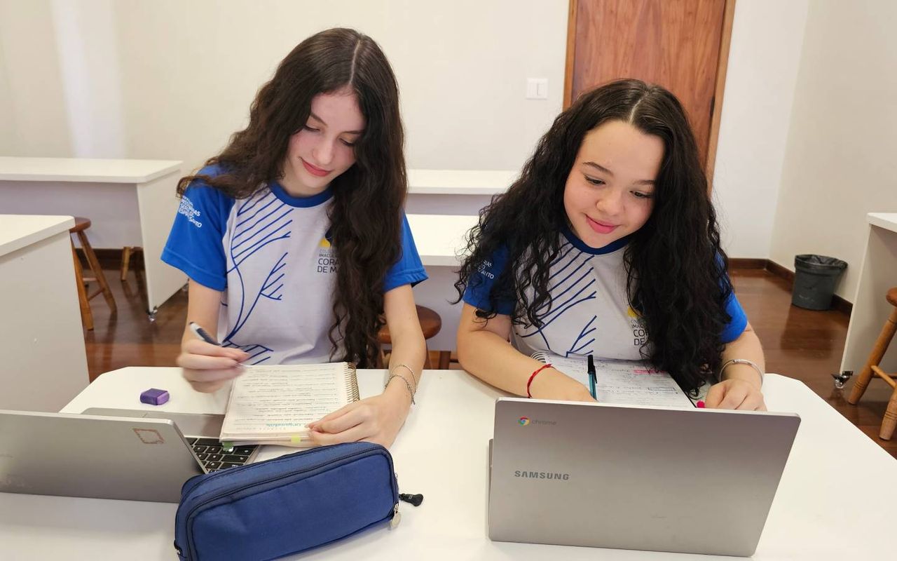 Duas estudantes do Ensino Médio estudam com cadernos e notebooks para o Projeto Aprova