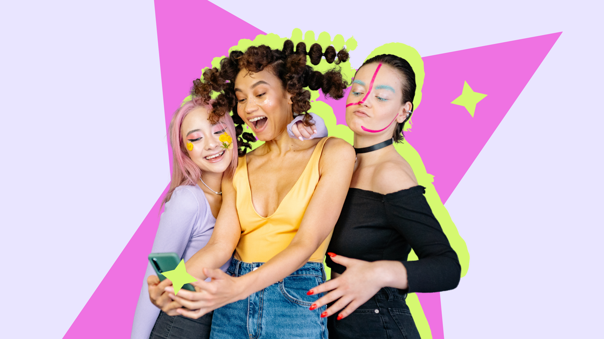 Three young women with colourful makeup taking a selfie together against a bright graphic backdrop.