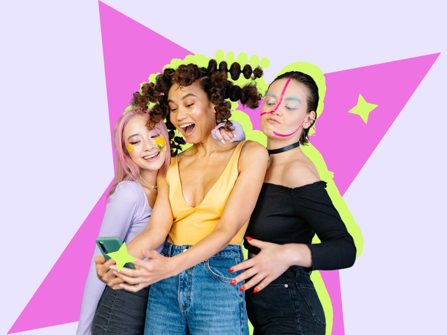 Three young women with colourful makeup taking a selfie together against a bright graphic backdrop.