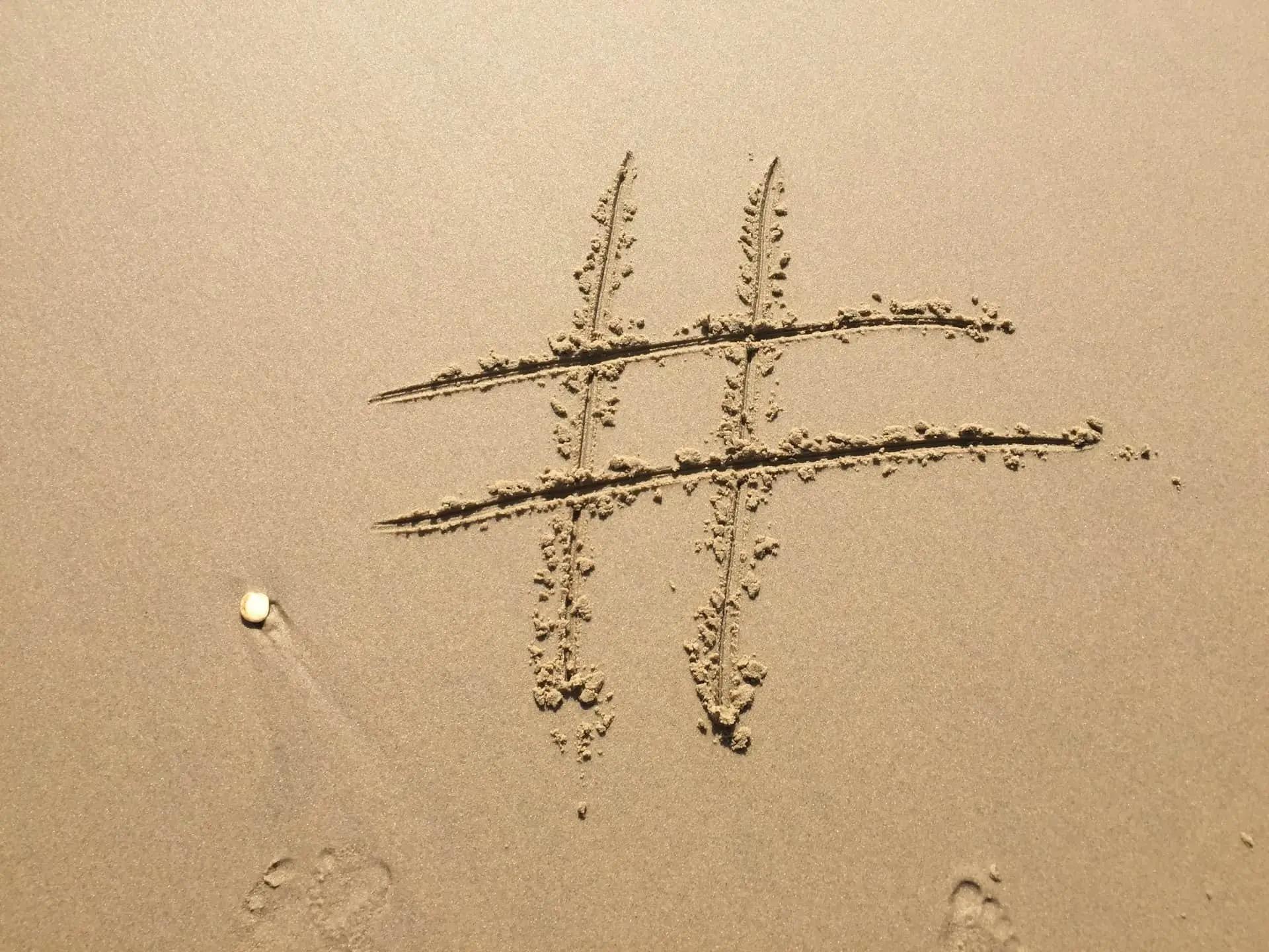 A hashtag symbol drawn in sand, with footprints nearby
