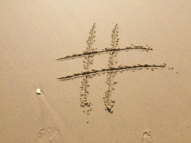 A hashtag symbol drawn in sand, with footprints nearby