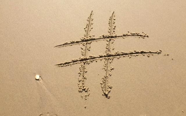 Un símbolo de hashtag dibujado en la arena, con huellas de pisadas cerca