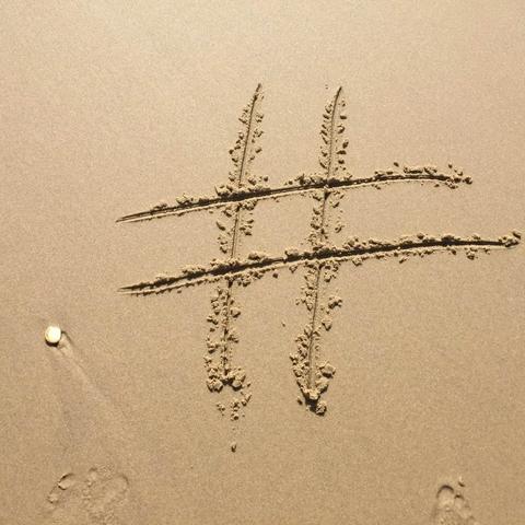 Un símbolo de hashtag dibujado en la arena, con huellas de pisadas cerca
