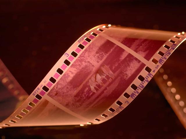 A strip of film with pink and purple hues, showing 'AGFA' and '3' on the edges, against a dark background.