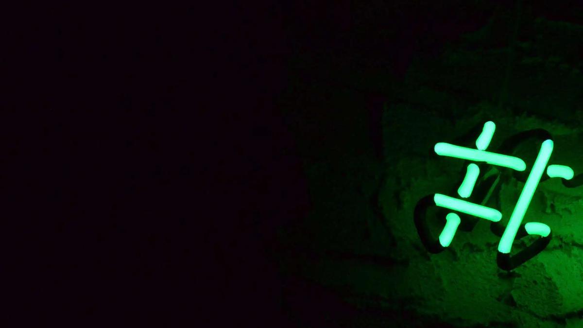 Símbolo de hashtag de neón verde brillando en la oscuridad sobre una pared de piedra