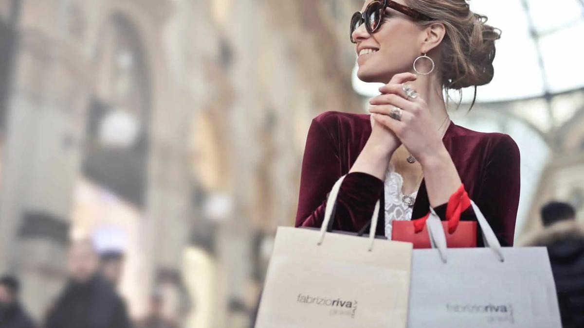 Smiling woman in sunglasses holding shopping bags on a city street