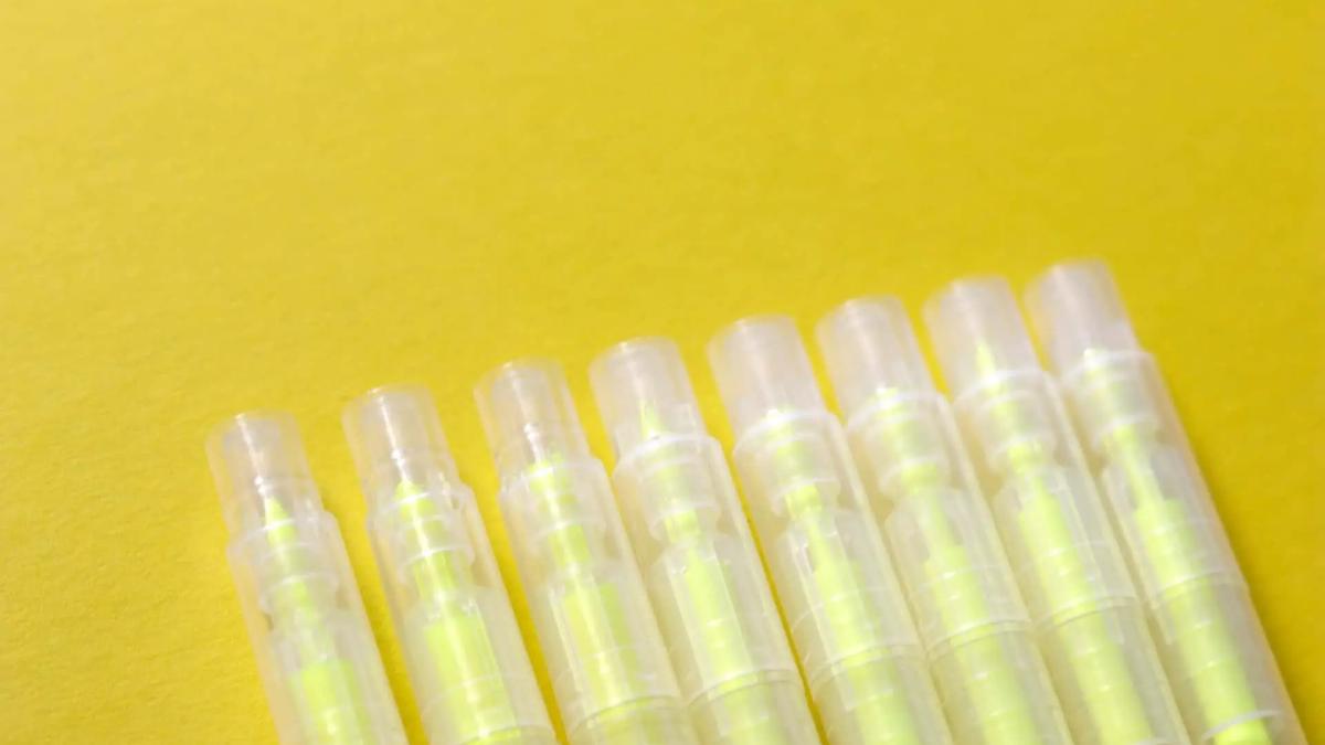 Seven clear highlighters with yellow ink, lined up diagonally on a bright yellow background. Bright, clean mood.
