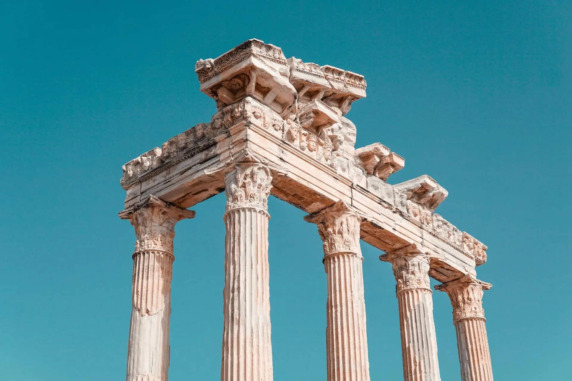 Ruins of ancient stone columns supporting a carved entablature against a blue sky