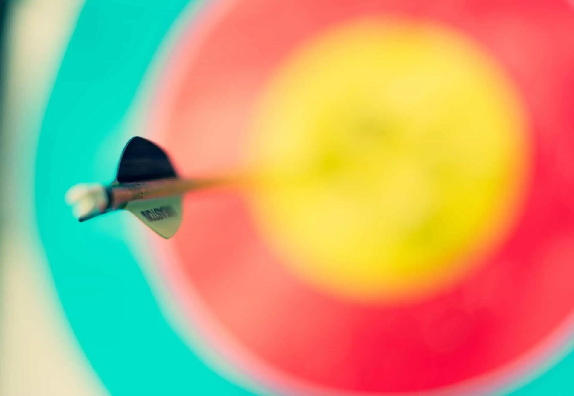 Close-up of an arrow embedded in the center of a colorful archery target