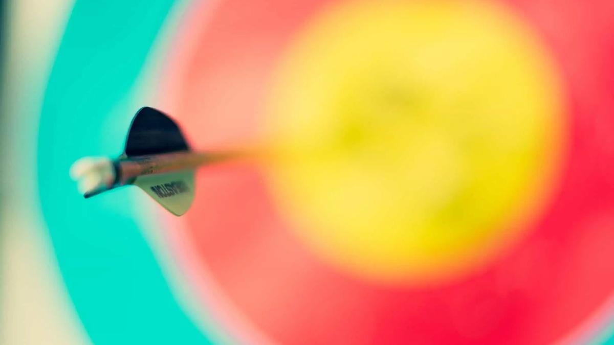 Close-up of an arrow embedded in the center of a colorful archery target