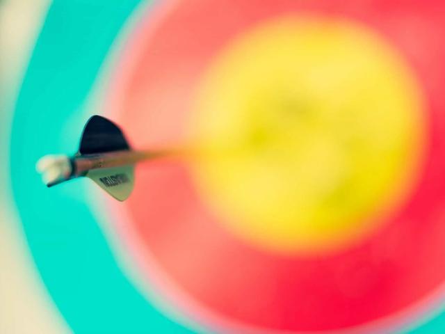 Close-up of an arrow embedded in the center of a colorful archery target