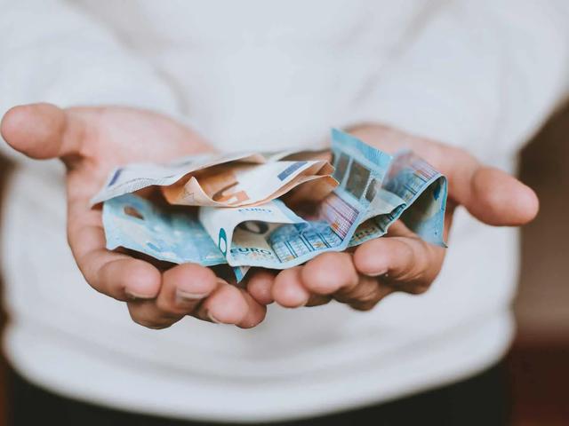 Cupped hands holding a crumpled fan of euro banknotes