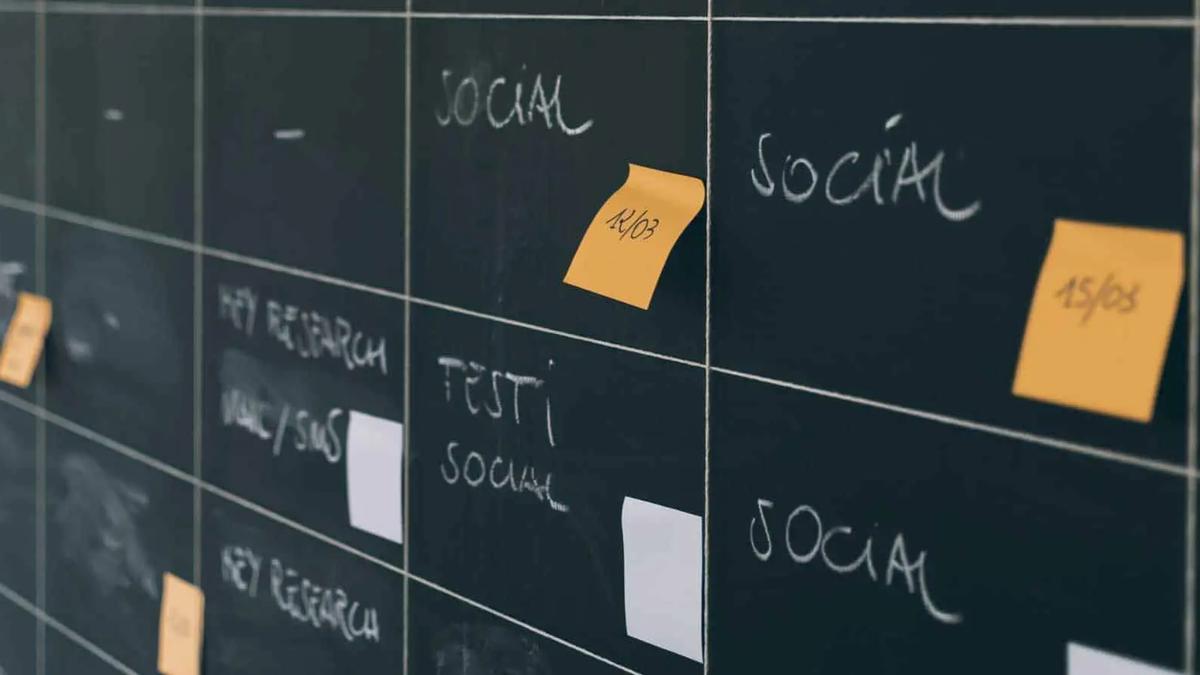 A blackboard planning grid with chalk labels like Social and orange sticky notes with dates