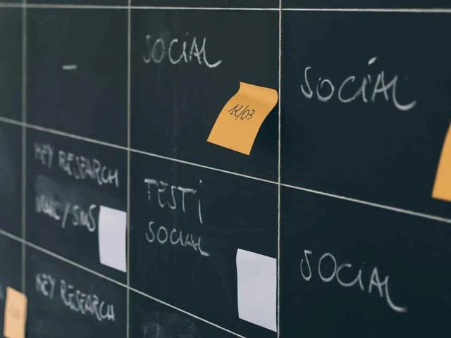 A blackboard planning grid with chalk labels like Social and orange sticky notes with dates