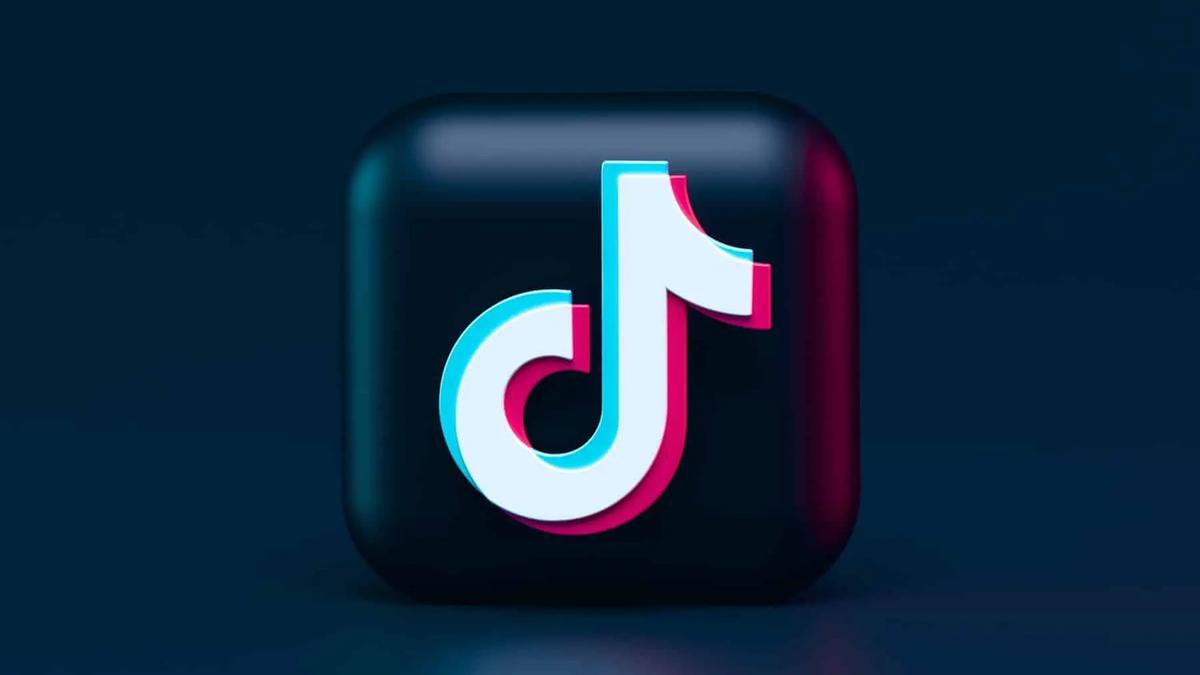 3D TikTok logo, white with pink and blue shadows, on a dark blue background with reflections. Modern, clean mood.