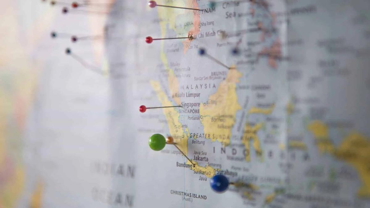 Close up of a map of Southeast Asia with colorful pushpins marking locations. Focus on Indonesia, Malaysia, Singapore.