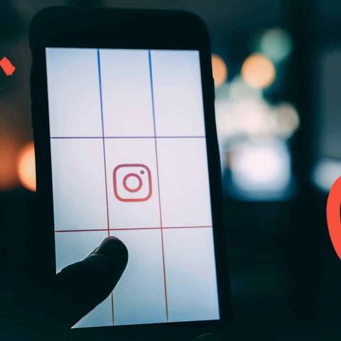 Una mano sostiene un teléfono con el logotipo de Instagram sobre una pantalla dividida en cuadrícula