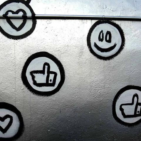 Silver wall with black and white graffiti of hearts, thumbs up, and a smiley face. Industrial, gritty mood.