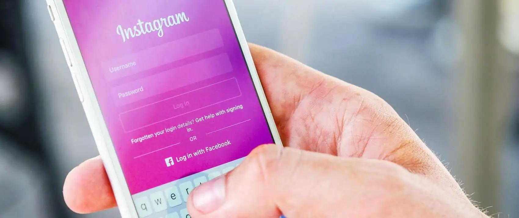 Una mano sostiene un teléfono con la pantalla de inicio de sesión de Instagram, con campos de usuario y contraseña